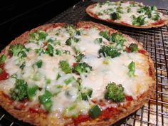 two pizzas with broccoli and cheese on them sitting on top of an oven rack