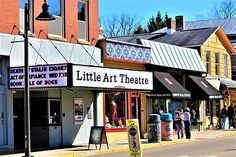 people are walking on the sidewalk in front of little art theatre