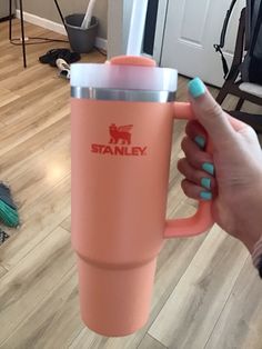 a person holding a pink coffee cup in their hand with the word stanley on it