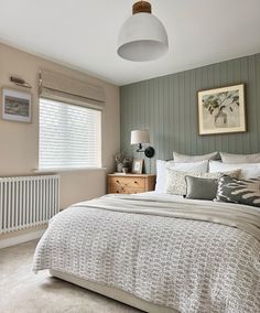 a bedroom with a bed, dresser and lamp in it's corner next to a window