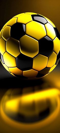 a yellow and black soccer ball sitting on top of a reflective surface with the light reflecting off it's side