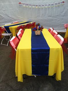 a blue and yellow table cloth with red, white and blue chair covers on it