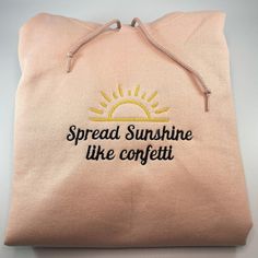 My everyday motto...spread sunshine like confetti! Beautiful blush pink colored hoodie with sun yellow and black embroidered accents. This hoodie is embroidered using an industrial embroidery machine. We use super soft, high quality Jerzee Sweatshirts. Color is Blush Pink 50/50 cotton/polyester Pill resistent fleece Front Pouch Pocket These sweatshirts are Unisex & preshrunk, please see size chart in listing photos for sizing information. Casual Pink Hoodie With Letter Embroidery, Pink Embroidered Hoodie For Fall, Pink Hoodie With Embroidered Logo For Spring, Pink Hoodie With Embroidered Text For Winter, Casual Pink Hoodie With Embroidered Graphics, Winter Pink Hoodie With Embroidered Text, Pink Hooded Hoodie With Custom Embroidery, Pink Cotton Hoodie With Letter Embroidery, Pink Embroidered Cotton Hoodie