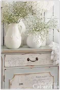 two white vases sitting on top of an old dresser