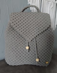 a gray crocheted bag sitting on top of a table next to a wall