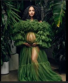 a woman in a green dress standing next to plants