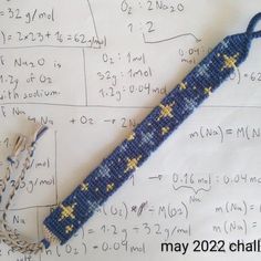 a blue and yellow beaded object on top of a sheet of paper with writing