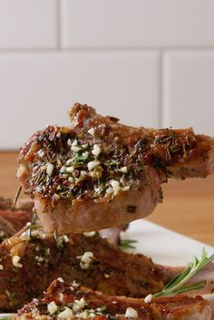 two pieces of meat on a plate with herbs and seasoning sprinkles