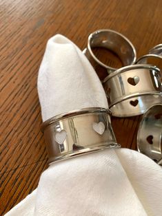 two napkin rings sitting on top of a wooden table next to each other with hearts drawn on them