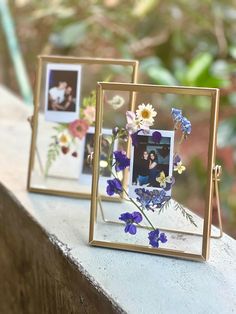 two frames with flowers are sitting on a ledge