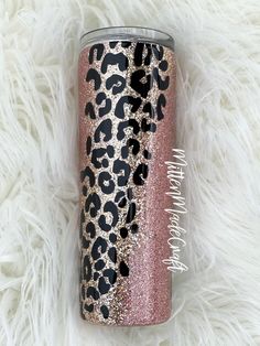 a pink and black leopard print tumbler cup on a white fur background with the words happy new year written in gold glitter