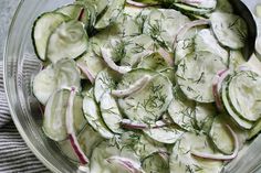 cucumber salad with dill and onions in a glass bowl on a table