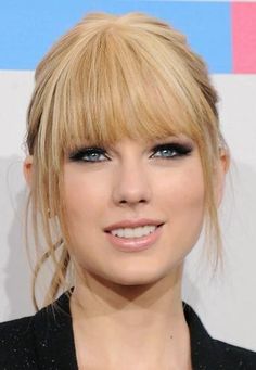 a close up of a person with blonde hair and blue eyeshadow, smiling