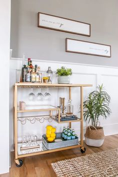 a bar cart with drinks on it next to a potted plant and some plants