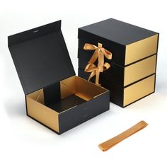 an open box with a gold bow on top and another black box in the bottom