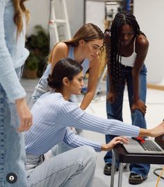 three women are looking at a laptop screen while another woman is working on the computer