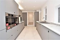 an empty kitchen with stainless steel appliances and marble counter tops, along with white walls