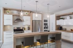 a modern kitchen with white cabinets and stainless steel appliances, along with bar stools