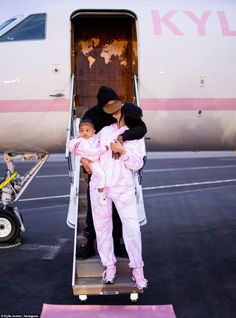 a woman and child getting off an airplane on the tarmac with their mother in her arms