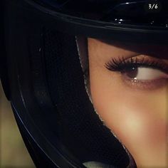 a woman's eye is seen through the visor of a motorcycle helmet