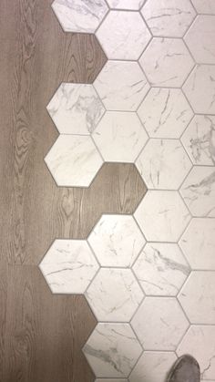 a person standing on the floor in front of a tile pattern that looks like hexagonal tiles