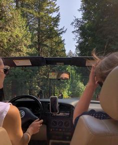 two women are sitting in the driver's seat of a car