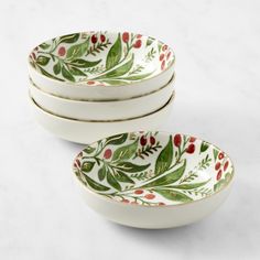 four white bowls with red berries and green leaves on them