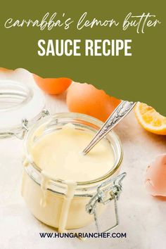 a glass jar filled with sauce next to an orange and some eggs on the table