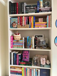 a bookshelf filled with lots of books next to a wall mounted disc clock