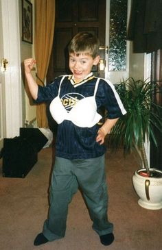 a young boy standing in front of a doorway with his fist up and smiling at the camera