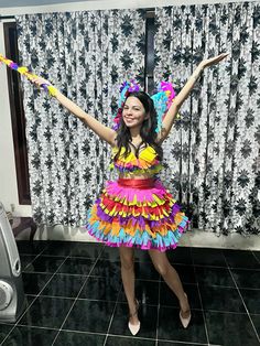 a woman in a brightly colored dress is holding her arms up and smiling at the camera