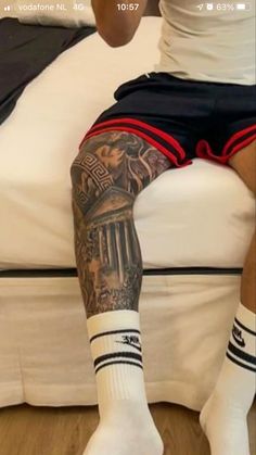 a man sitting on top of a bed next to a white pillow covered in tattoos