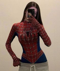 a woman is taking a selfie with her cell phone wearing a spiderman costume