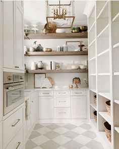 a kitchen with white cabinets and shelves filled with dishes