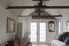 a living room with white walls and wood flooring next to a wooden door that leads to a patio