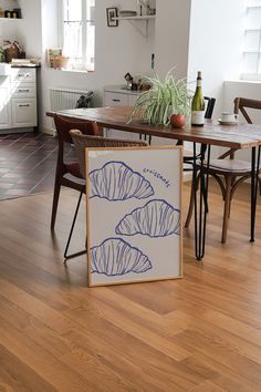 a table and chairs in a room with wood flooring next to a painting on the wall