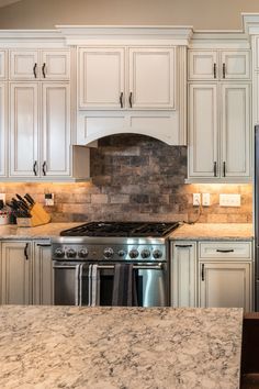 a kitchen with white cabinets and granite counter tops, stainless steel appliances and an oven