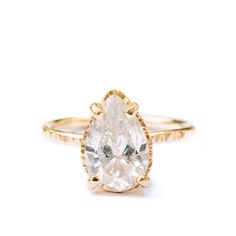 Fresh and dewy, for a lifetime! We love the Summer Rain engagement ring for it's fresh-cut flora feel, romantic and girly and vivacious. A three carat, pear-shaped moissanite, clear and nearly colorless, stands out in a hammered golden halo setting, on a slim and gamine 1.5mm band of burnished yellow gold. Pear Moissanite Nearly Colorless 12x8mm 3ct Hammered Halo Basket Setting Hammered 1.5mm Band 14k Yellow Gold White Pear Shaped Ring With Rose Cut Diamonds, Teardrop Diamond Ring For Proposal, Teardrop Rose Cut Diamond Proposal Ring, Anniversary Rose Cut Diamond Pear Shaped Ring, Pear Shaped Rose Cut Diamond Ring For Proposal, Pear-shaped Rose Cut Diamond Rings For Proposal, Pear-shaped Rose Cut Diamond Proposal Ring, Teardrop Prong Setting Ring For Proposal, Hammered Engagement Ring