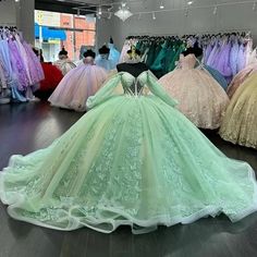 there are many dresses on display in the store, and one is wearing a green gown