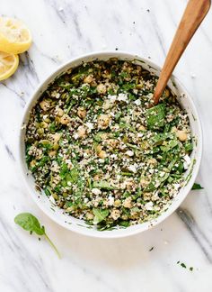 a white bowl filled with spinach and feta cheese next to sliced lemons