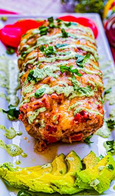 an enchilada roll is on a plate with avocado and tomatoes