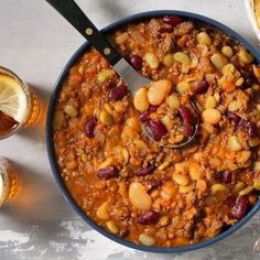 a bowl filled with chili and beans next to two glasses