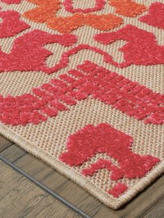 a red and orange rug on top of a wooden floor