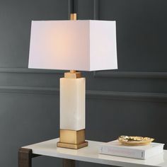 a table with a lamp on top of it and a book sitting next to it