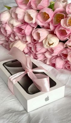 an apple box with two pairs of shoes in it next to pink tulips