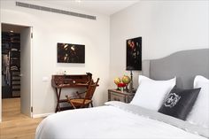 a bedroom with white bedding and paintings on the wall next to an open closet