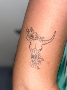 a tattoo on the arm of a person with a cow's head and flowers