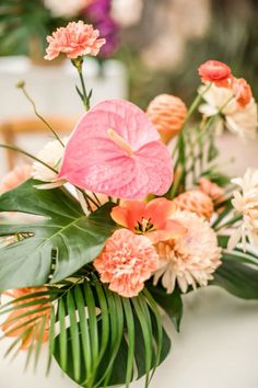 an arrangement of flowers and greenery on a table