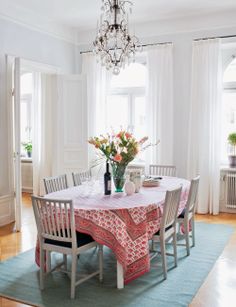 a dining room table with chairs and a chandelier hanging from the ceiling above it