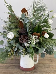 a white vase filled with flowers and greenery